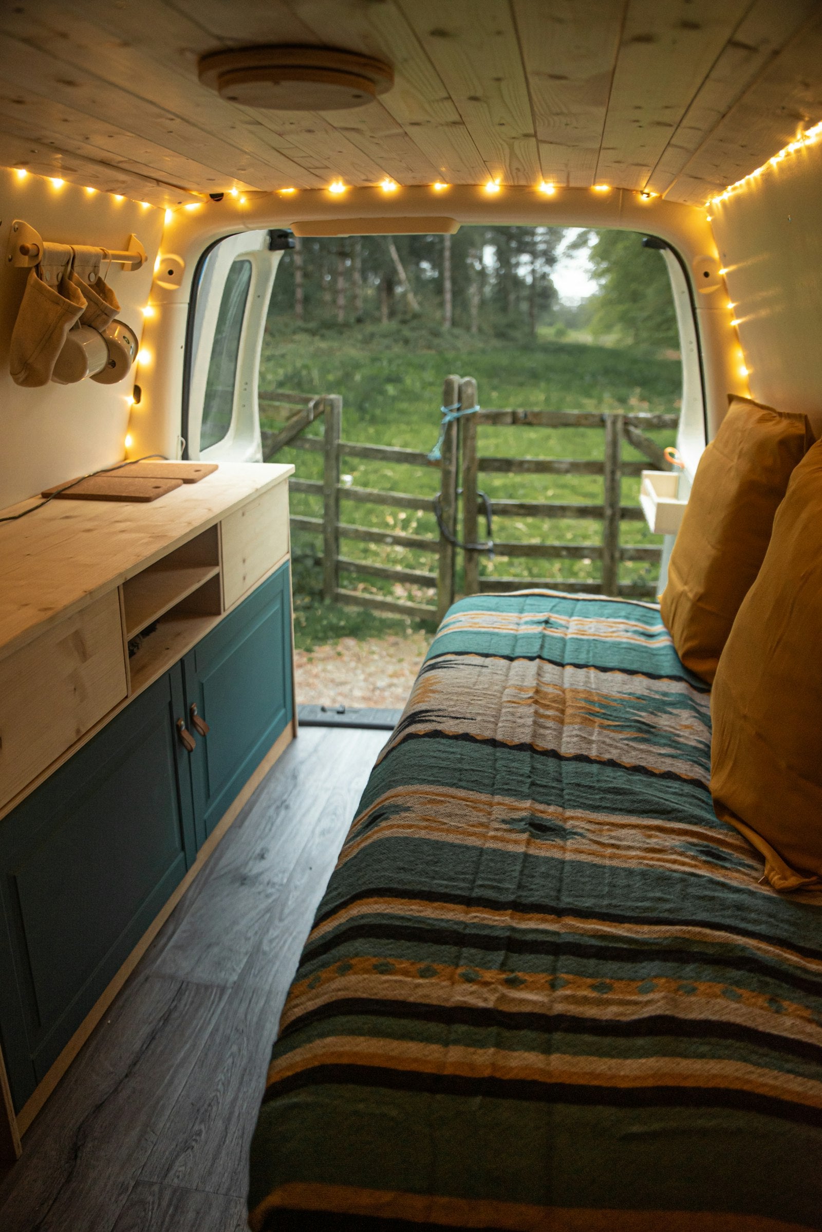Converted van interior with a roof window and a bed
